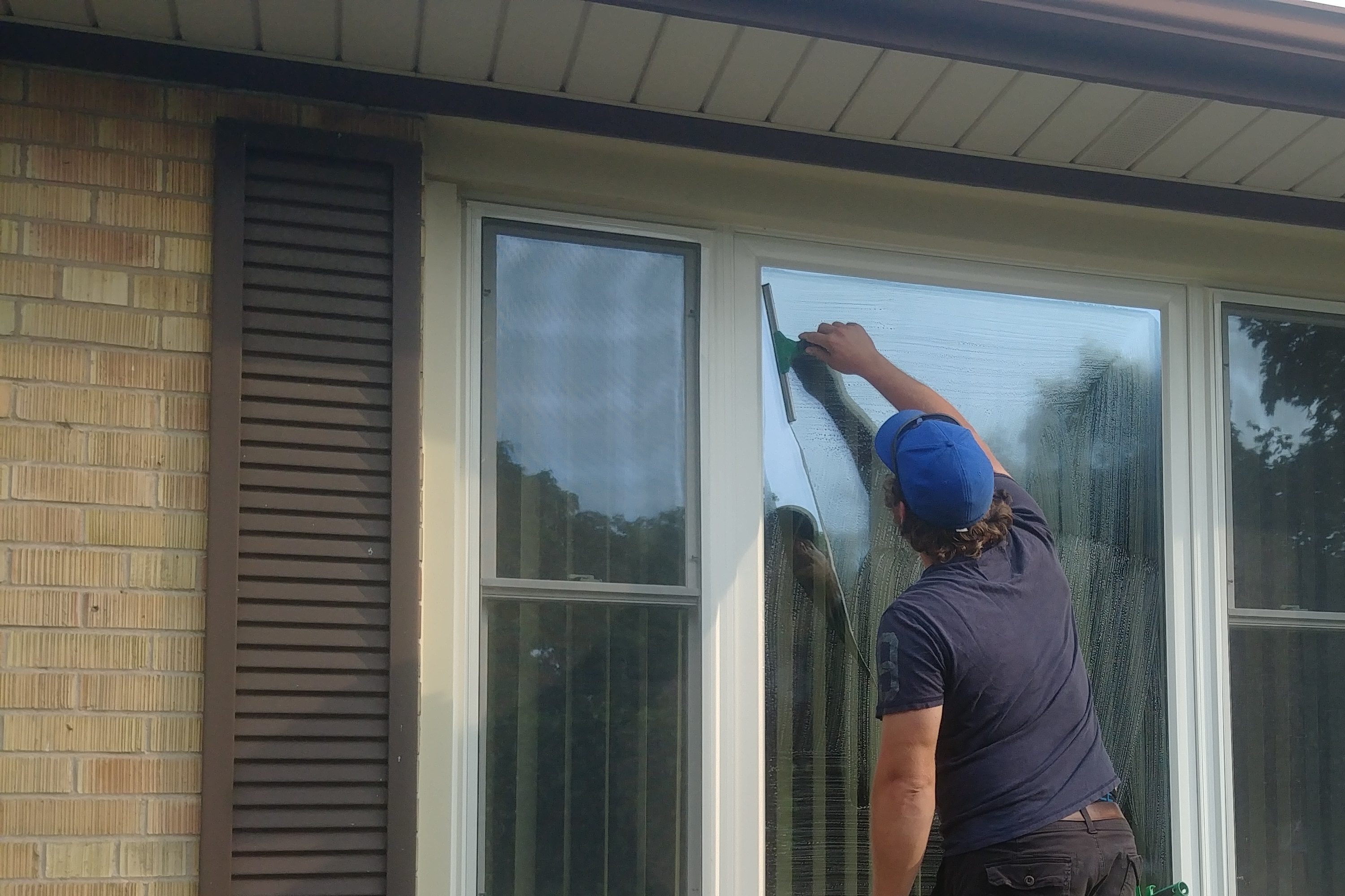 Window cleaner working on residential windows with squeegee